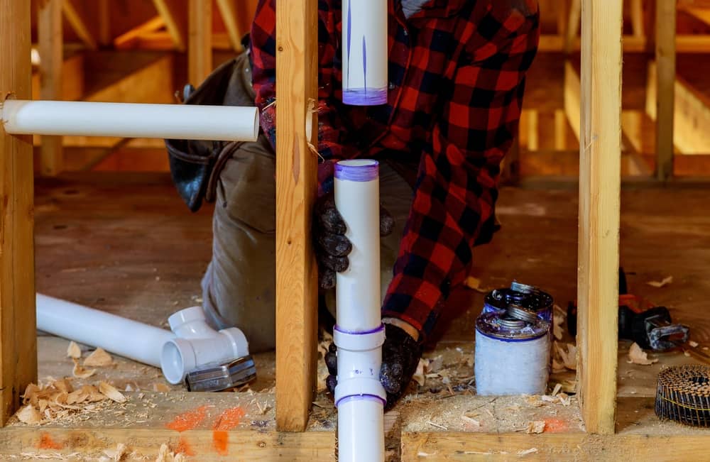 Plumber installing PVC Pipe at new construction